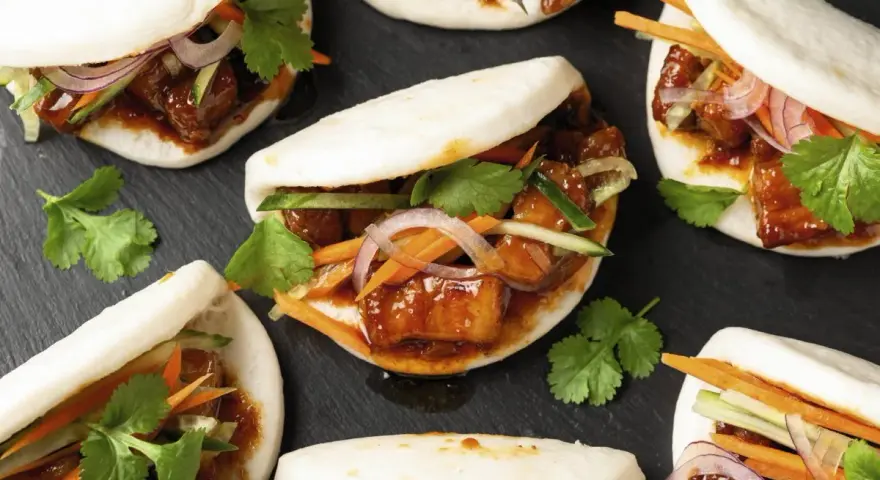 Bao nourriture : petits pains moelleux garnis de porc braisé, de concombre, de carottes et de coriandre fraîche.
