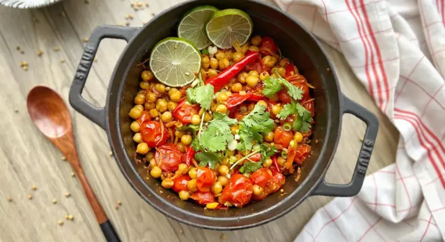 Un délicieux curry thaï végétarien aux pois chiches, tomates et coriandre, garni de quartiers de citron vert.