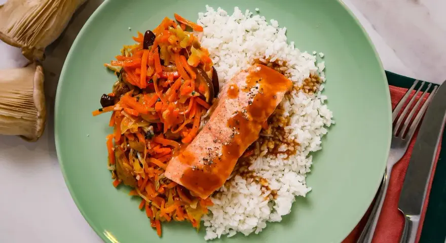 Filet de saumon nappé de sauce teriyaki, servi avec du riz blanc et une julienne de légumes croquants.