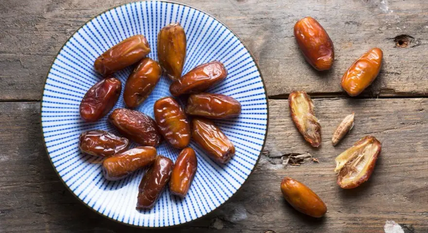 Assiette de dattes sur fond de bois. Une personne souffrant d'allergie aux dattes ne peut pas en manger.