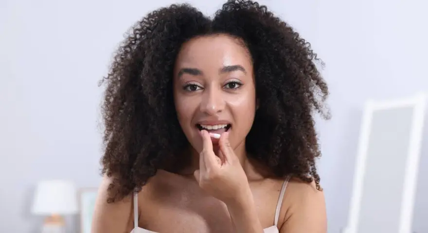 Femme aux cheveux bouclés prend une gélule. Elle se demande si le collagène marin peut causer une allergie.