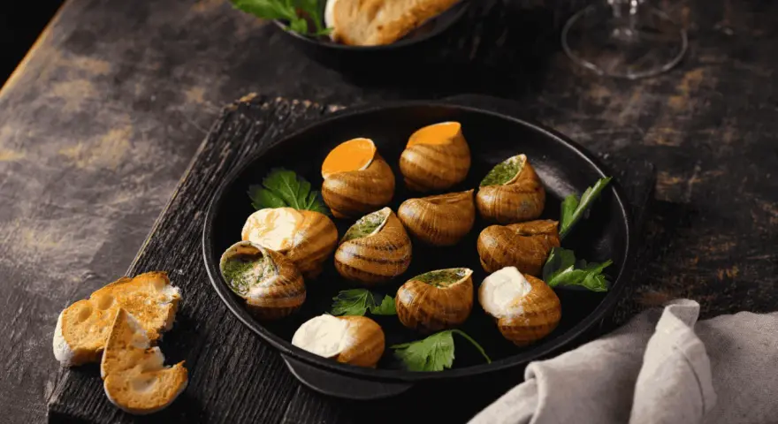 Plat d'escargots à l'ail et persil, servi avec du pain grillé. Attention, une allergie escargot peut survenir !
