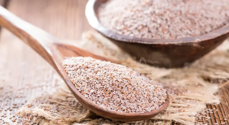 Graines de psyllium sur une cuillère en bois, un remède naturel pour un transit régulier.