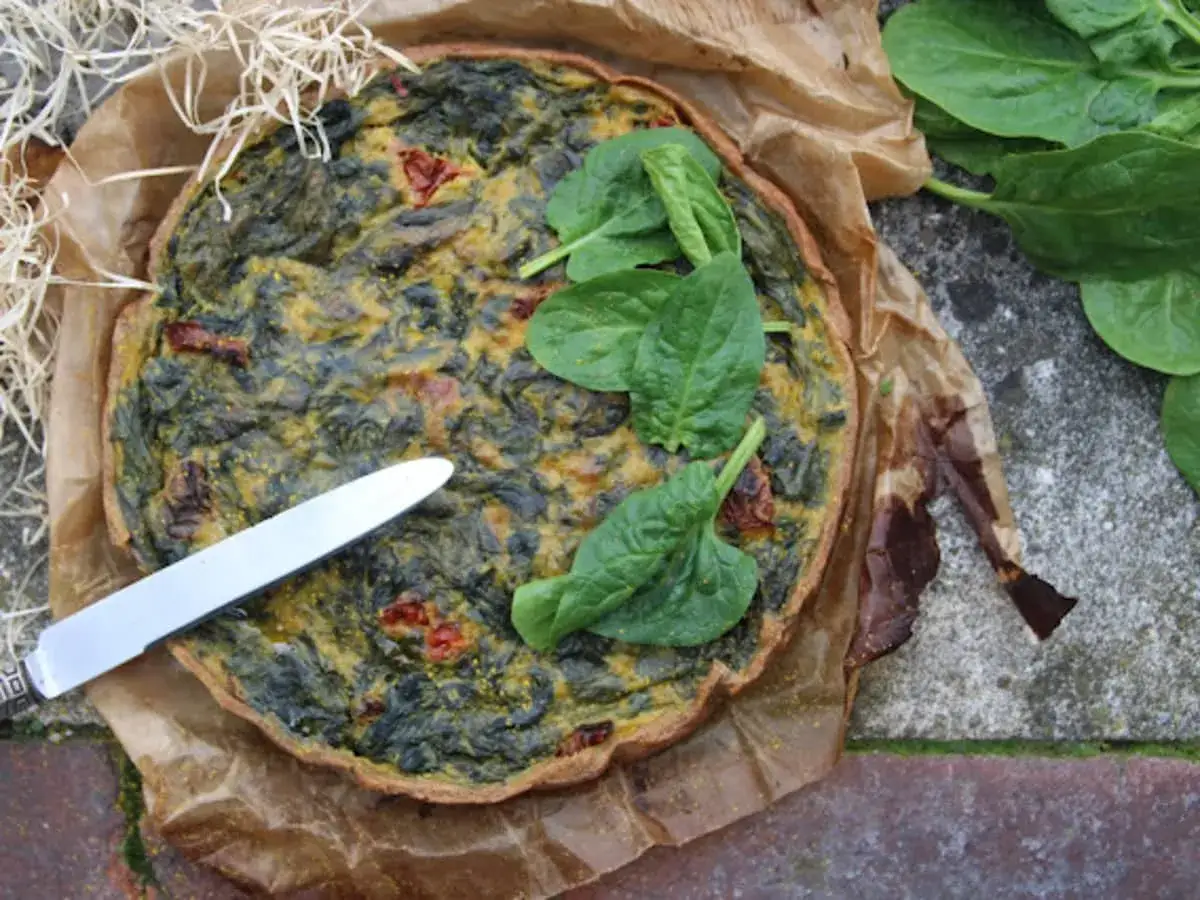 Tarte sal&eacute;e aux &eacute;pinards et tomates s&eacute;ch&eacute;es, une d&eacute;licieuse recette d'&eacute;pinard. Une feuille de fraisier d&eacute;core le dessus.