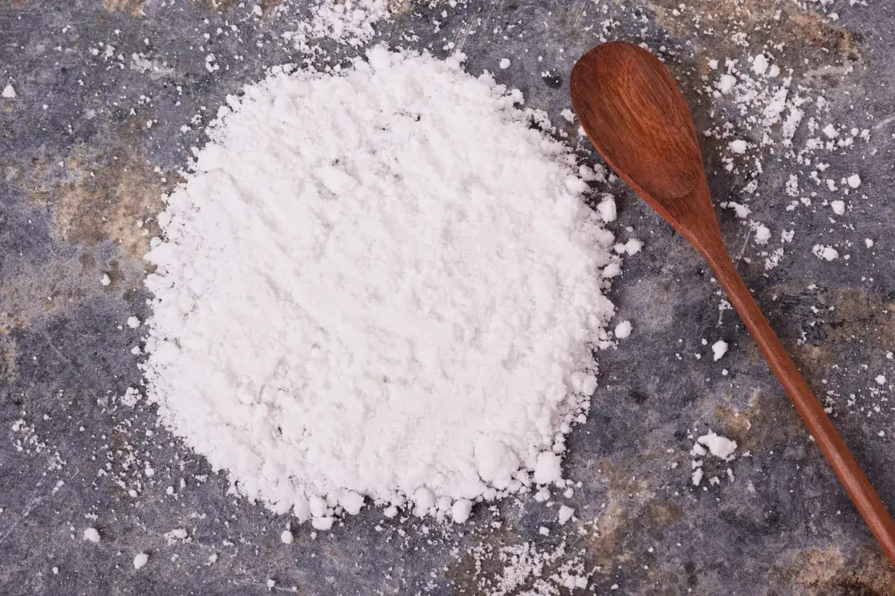 Une cuill&egrave;re en bois repose pr&egrave;s d'une poudre blanche, id&eacute;ale par quoi remplacer la f&eacute;cule de pomme de terre pour &eacute;paissir vos sauces.