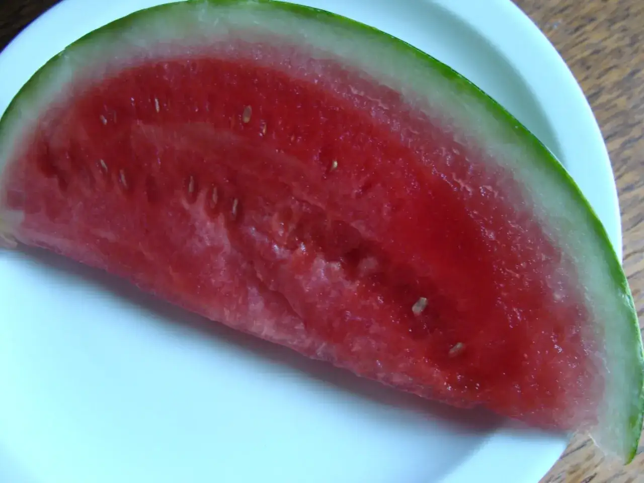 Tranche de pasteque bienfait sur une assiette blanche. Un délice rafraîchissant et plein de vitamines.