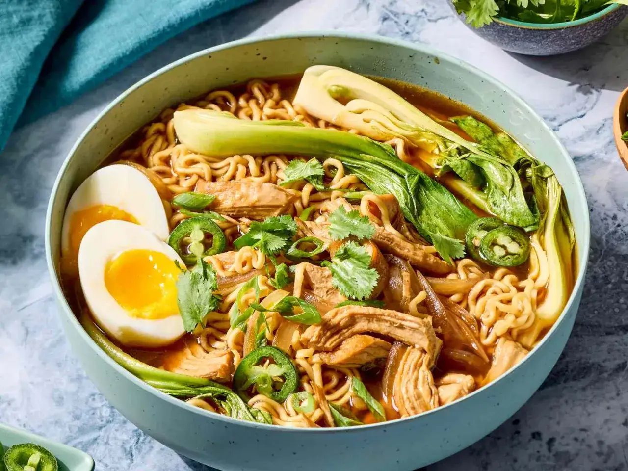 Un bol de ramen de poulet fumant avec des nouilles, des &oelig;ufs mollets, du bok choy et des jalape&ntilde;os.