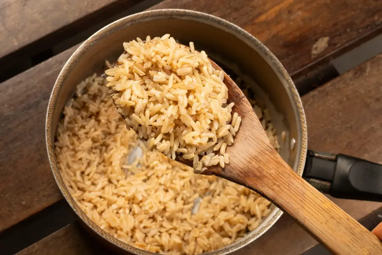Une cuill&egrave;re en bois sert du riz complet fra&icirc;chement cuit, pr&ecirc;t &agrave; &ecirc;tre d&eacute;gust&eacute;.