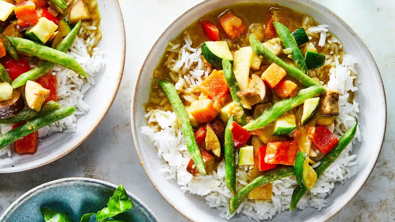 Un plat de riz blanc garni d'un curry vert aux l&eacute;gumes color&eacute;s : haricots verts, courgettes, poivrons et carottes.