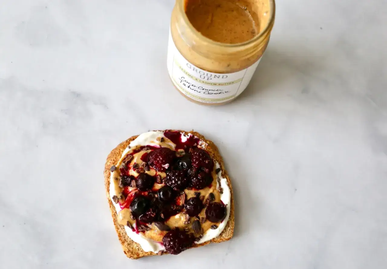 Tartine de pain grill&eacute; avec une cr&egrave;me onctueuse, des baies et des &eacute;clats de cacao. Un pot de beurre de s&eacute;same et de cajou, une excellente alternative par quoi remplacer le beurre de cacahu&egrave;te.