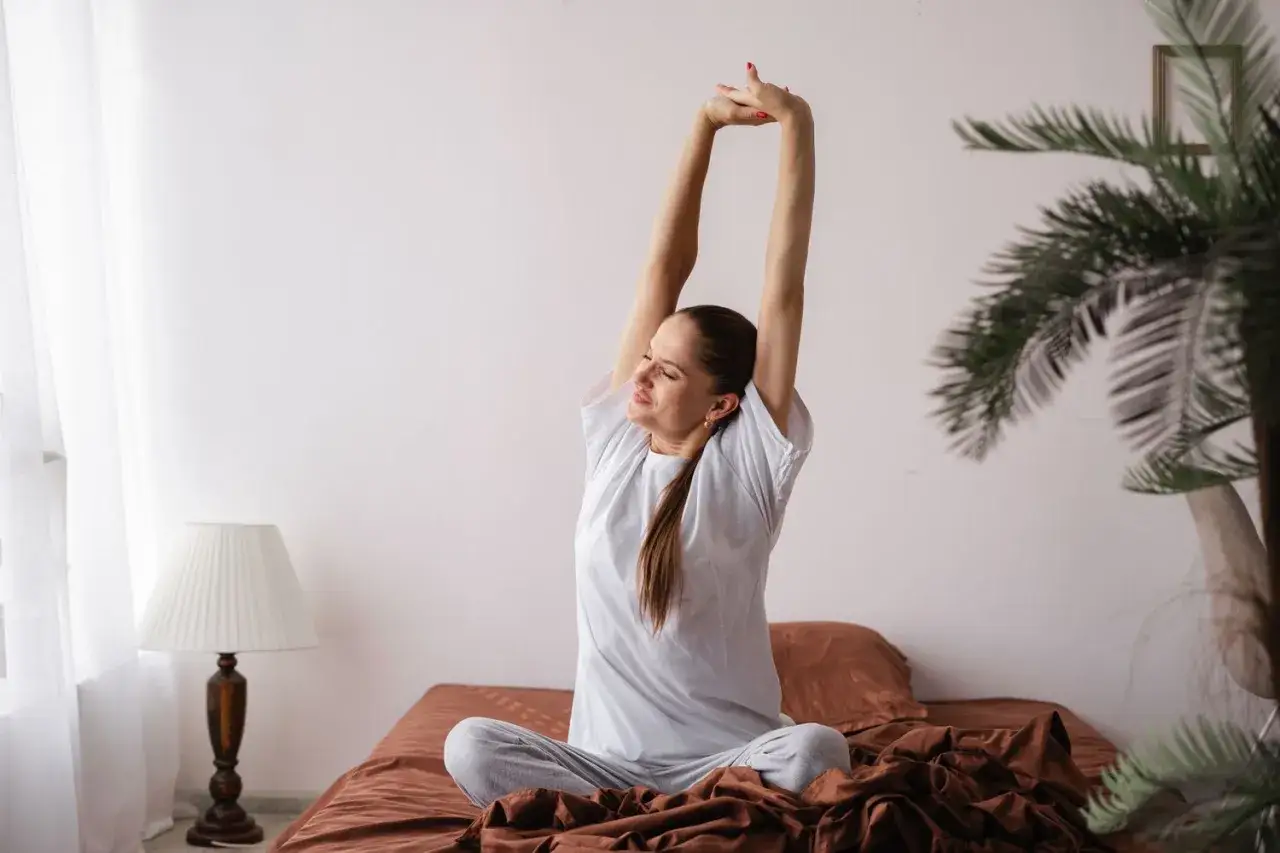 Une femme s'&eacute;tire sur son lit, pr&ecirc;te &agrave; commencer sa journ&eacute;e avec &eacute;nergie, comme apr&egrave;s un bon caf&eacute; et une dose de rhodiola.
