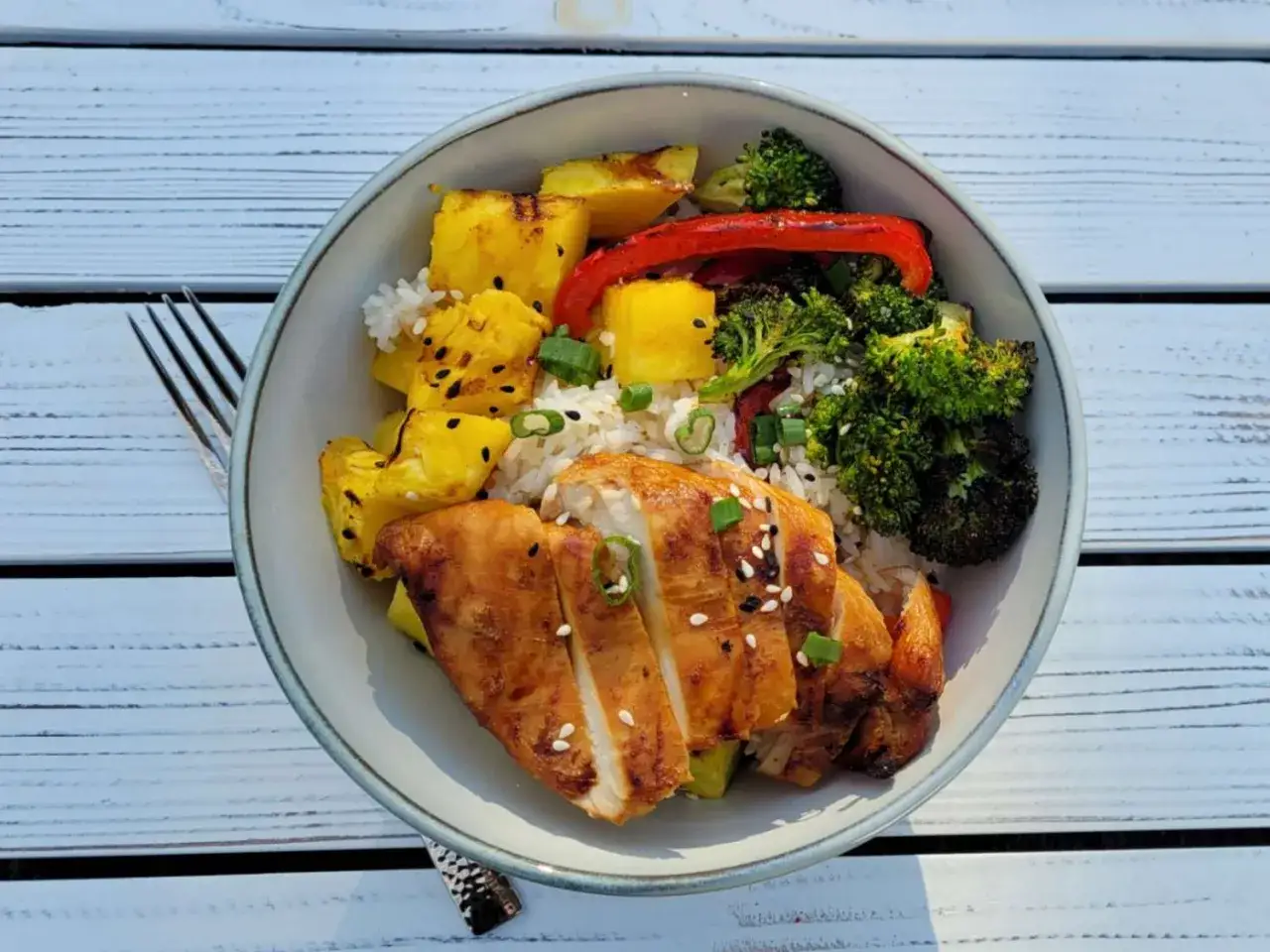 Bol de riz teriyaki avec poulet grill&eacute;, ananas r&ocirc;ti, brocolis et poivrons rouges. Garniture de graines de s&eacute;same et ciboule.
