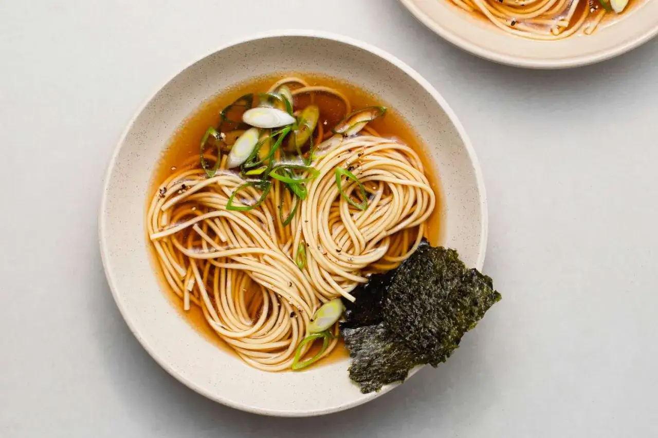 Un bol de ramen japonais traditionnel, avec des nouilles fines, du bouillon clair, des oignons verts et une feuille d'algue nori.
