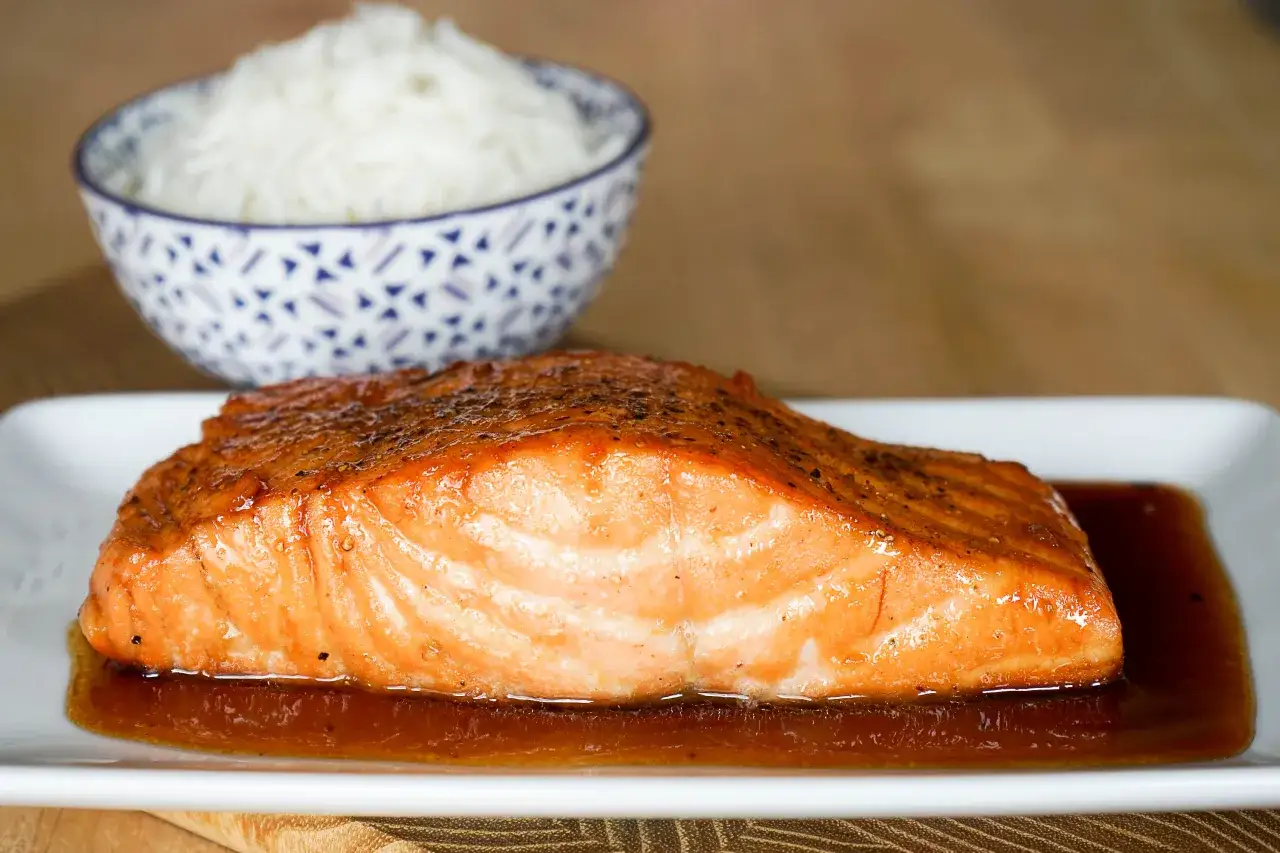 Un d&eacute;licieux saumon sauce soja sucr&eacute;e, laqu&eacute; et brillant, servi avec du riz blanc dans un bol orn&eacute;.